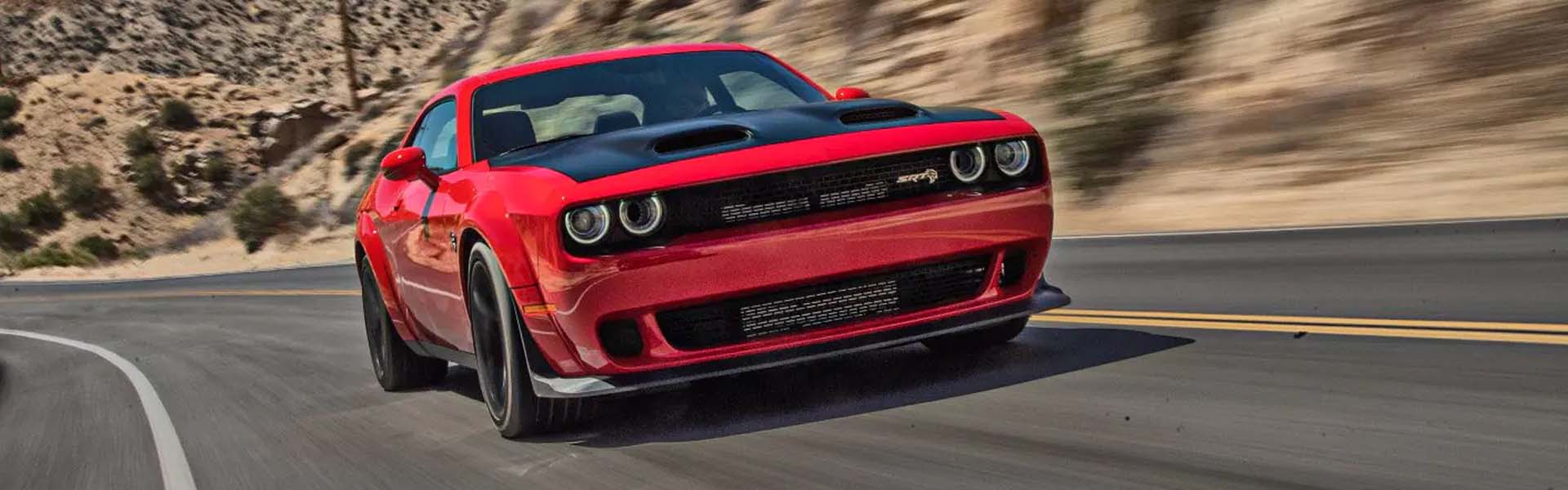 A red challenger driving on the road.