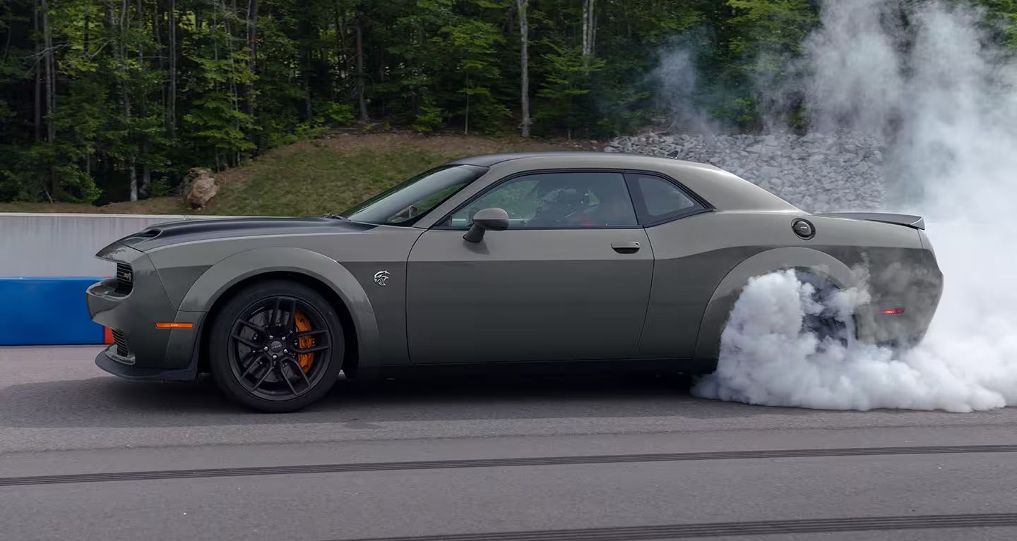 A gray car burning out on the road.