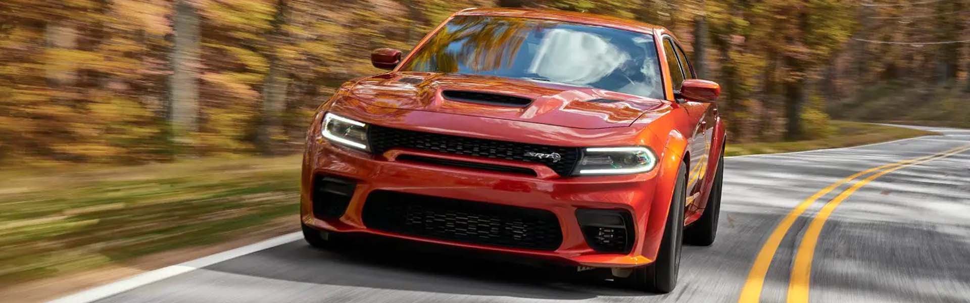 A oranger charger driving on the road.