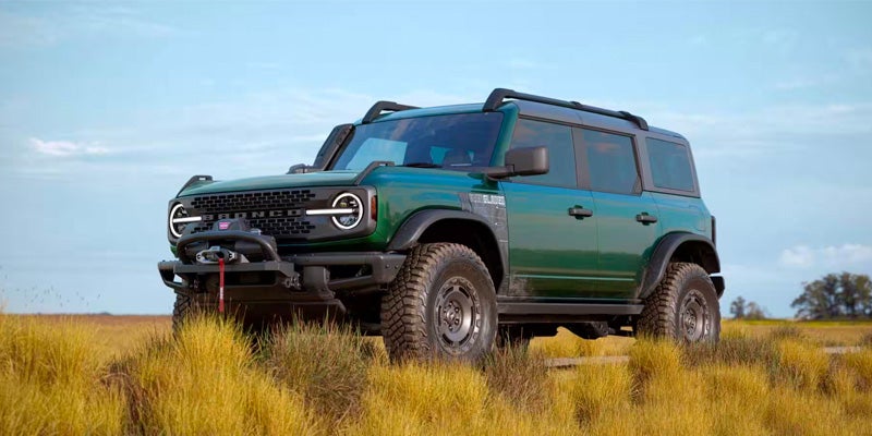 A green bronco sitting in a field.