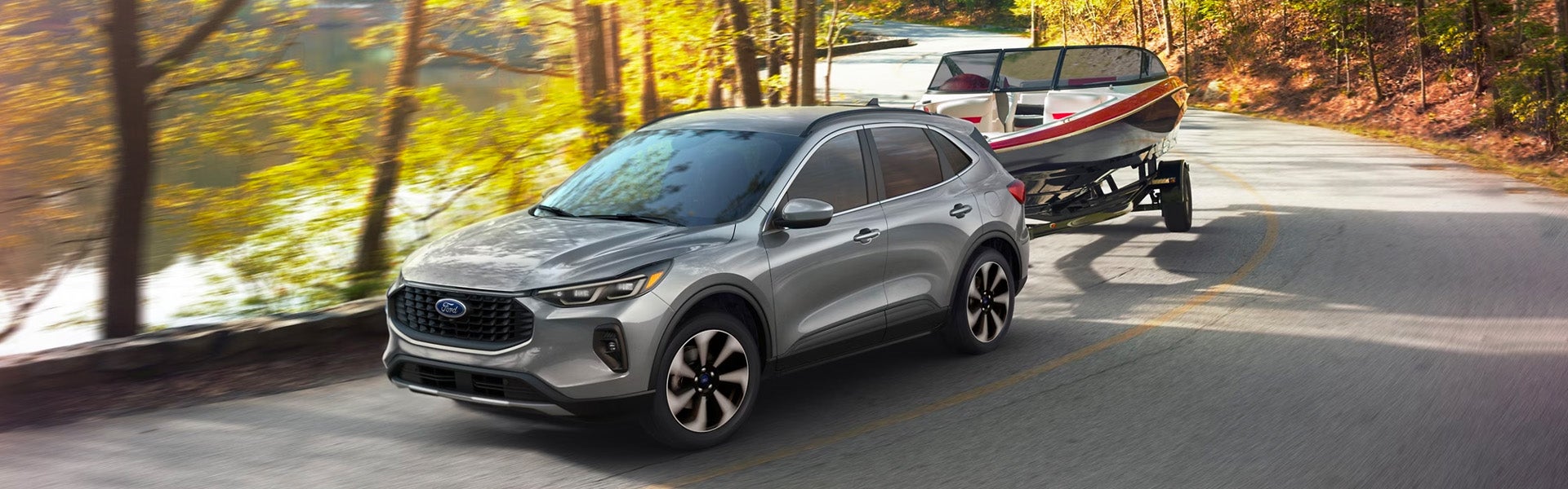 A silver car pulling a trailer witha boat on it.