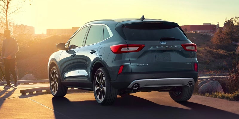 A blue car parked towards the sunset.