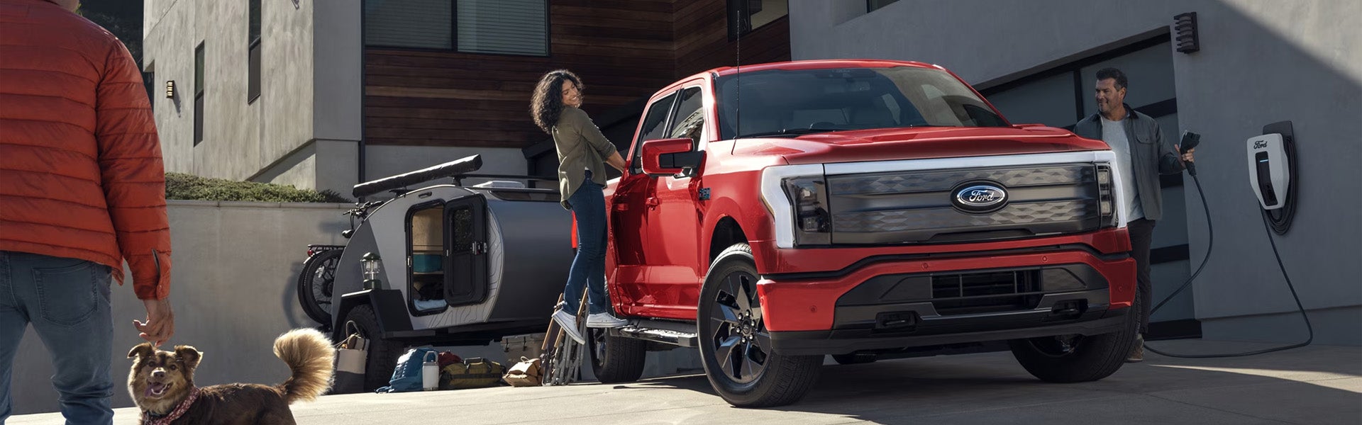 A woman standing next to a red f-150 lightning.