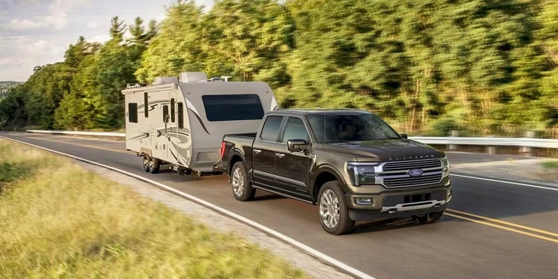 A Ford f-150 pulling a trailer down the road.