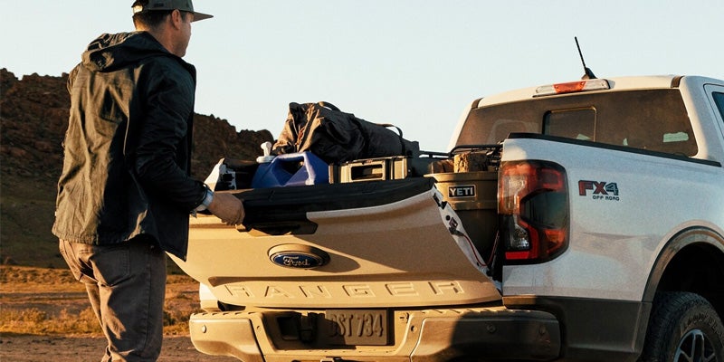 A man getting into the bed of a ford ranger.
