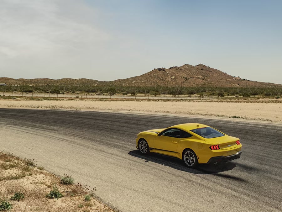 A yellow mustang driving on the road.