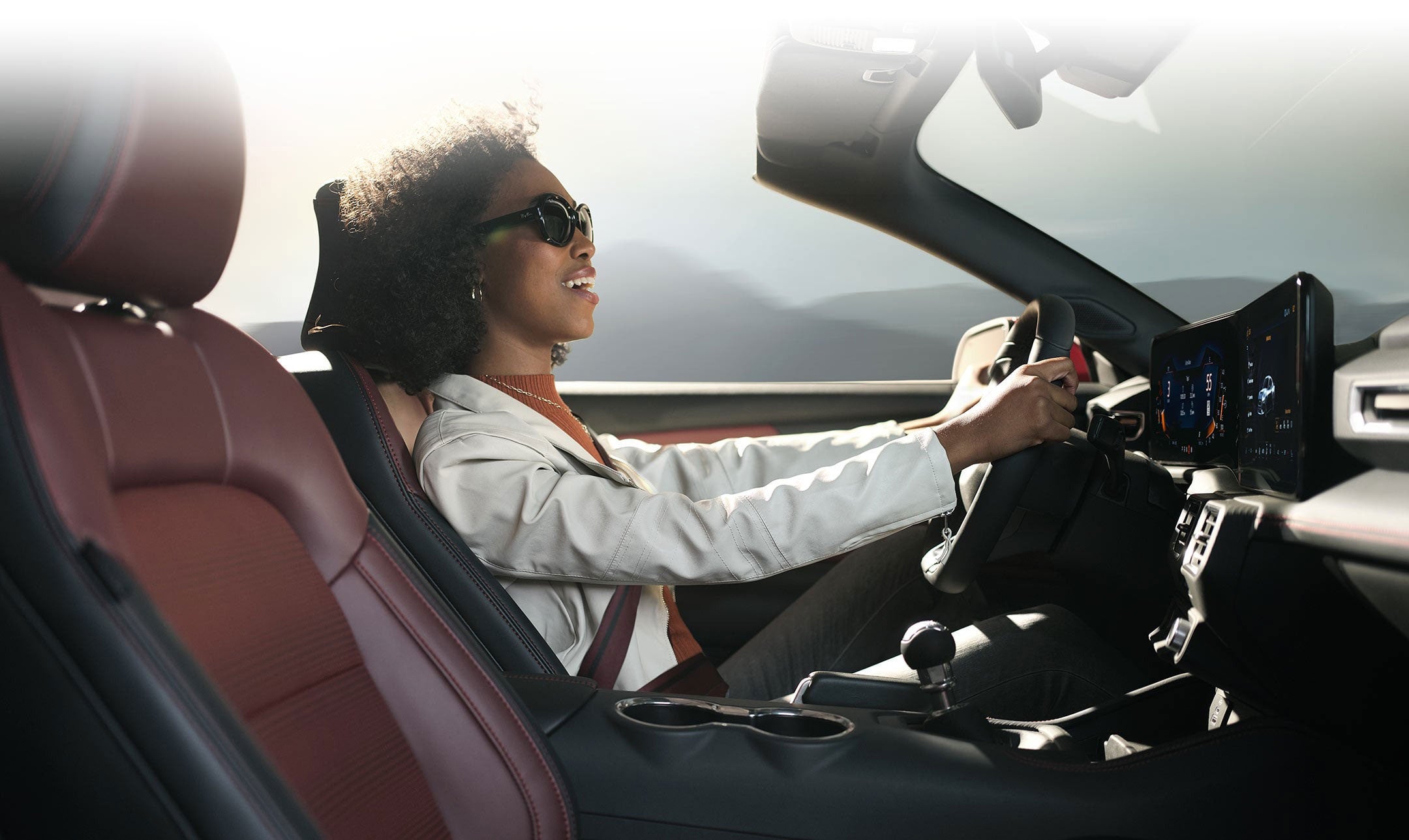 A woman in the driver seat of a mustang.