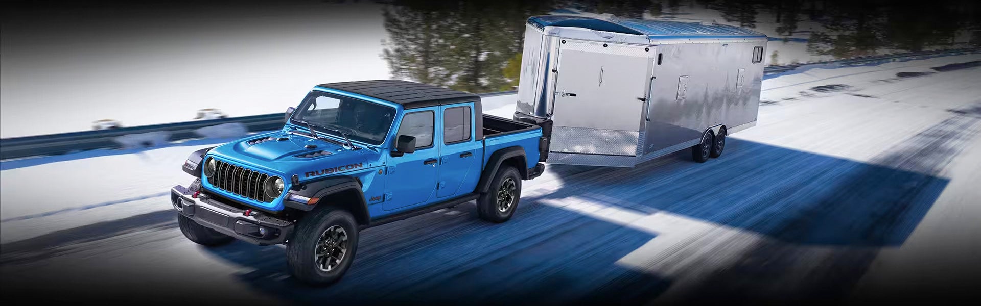 A blue jeep pulling a trailer in the snow.
