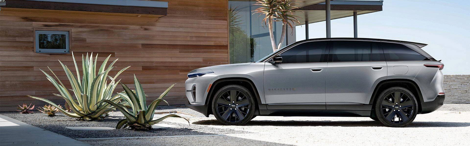 A woman walking next to a silver wagoneer s.