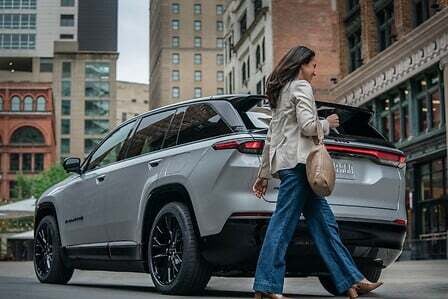 A woman walking past a silver suv.