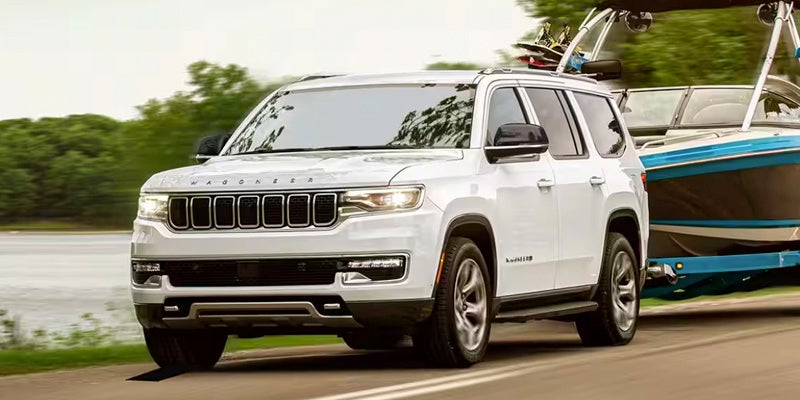 A white suv pulling a boat.