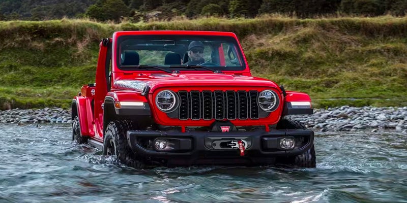 A red jeep driving through water.