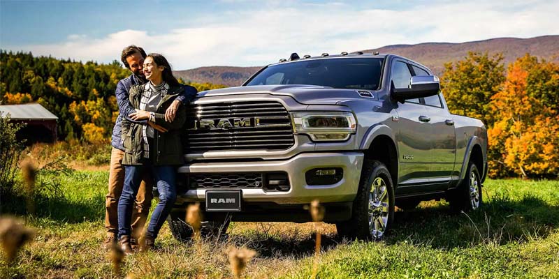 A man and woman next to a silver truck.