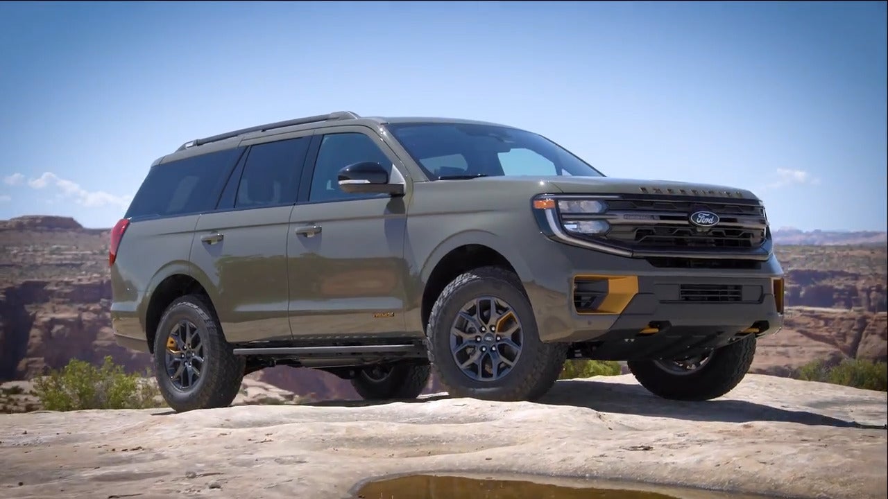 A green suv sitting parked on a rock.