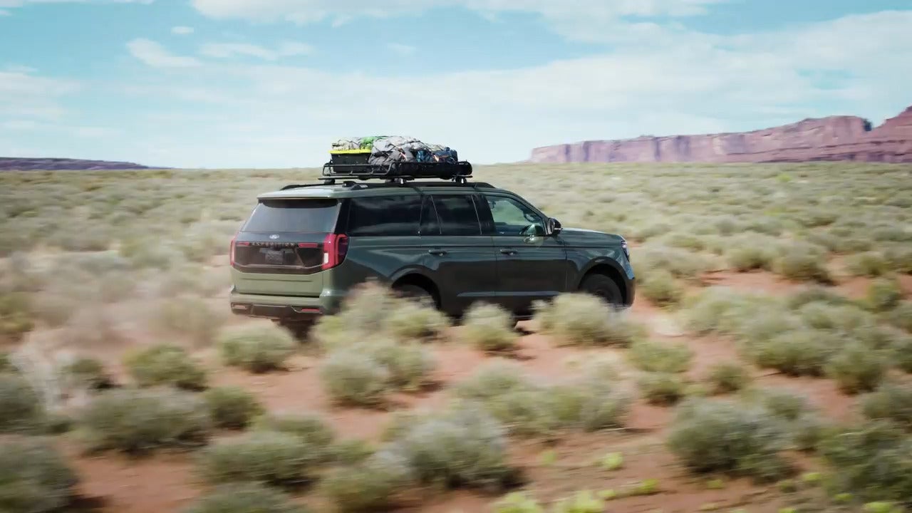 A green suv driving through the desert.