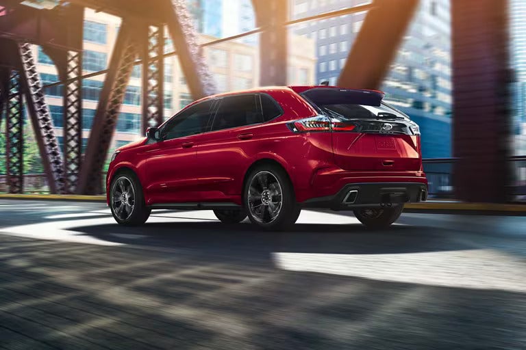 A red suv driving on a ridge.