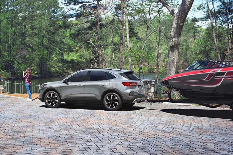 A silver car pulling a ttrialer with on boat.