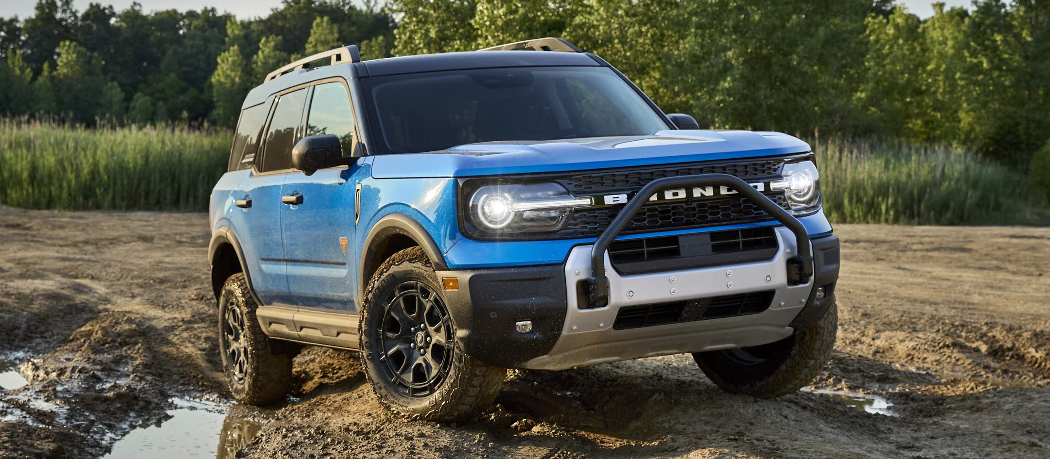 A blue bronco sport on a dirt hill.