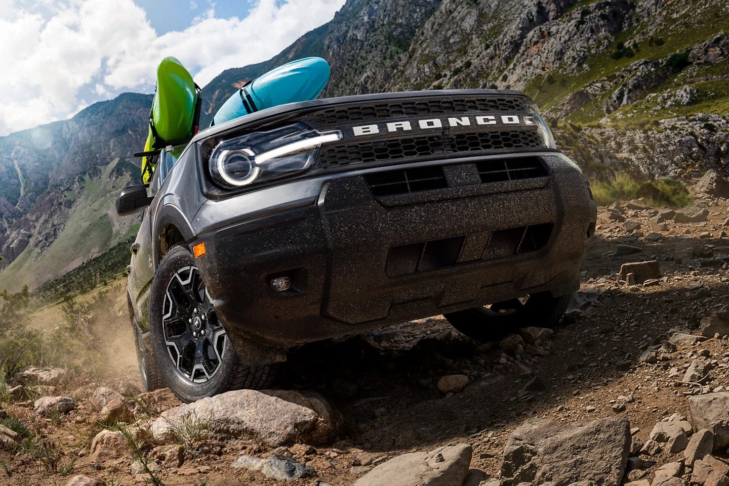 A green bronco spor going up a hill.