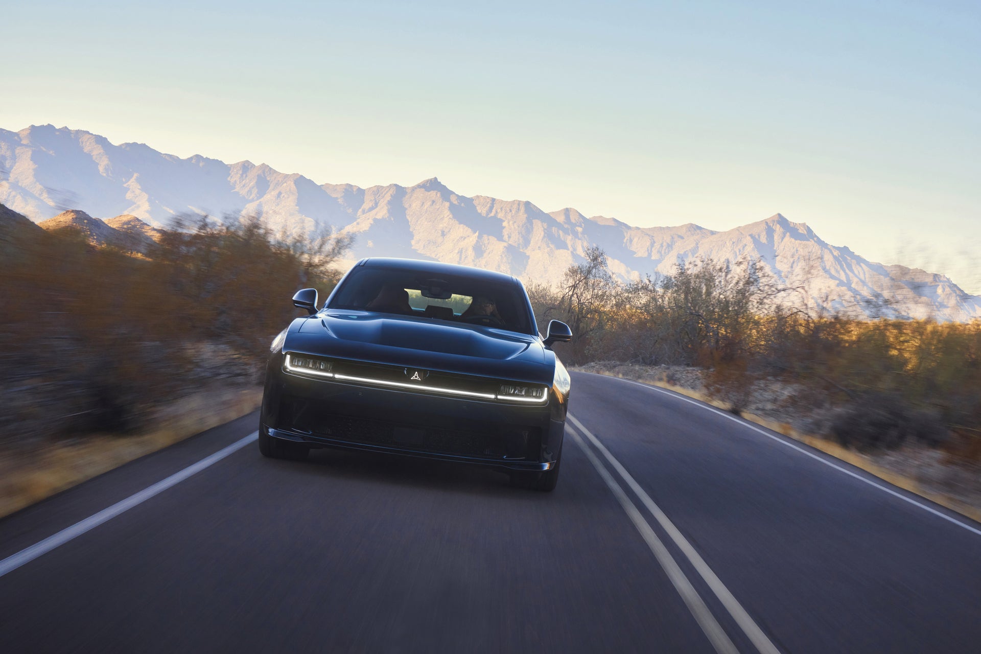 A blue car driving down the raod.