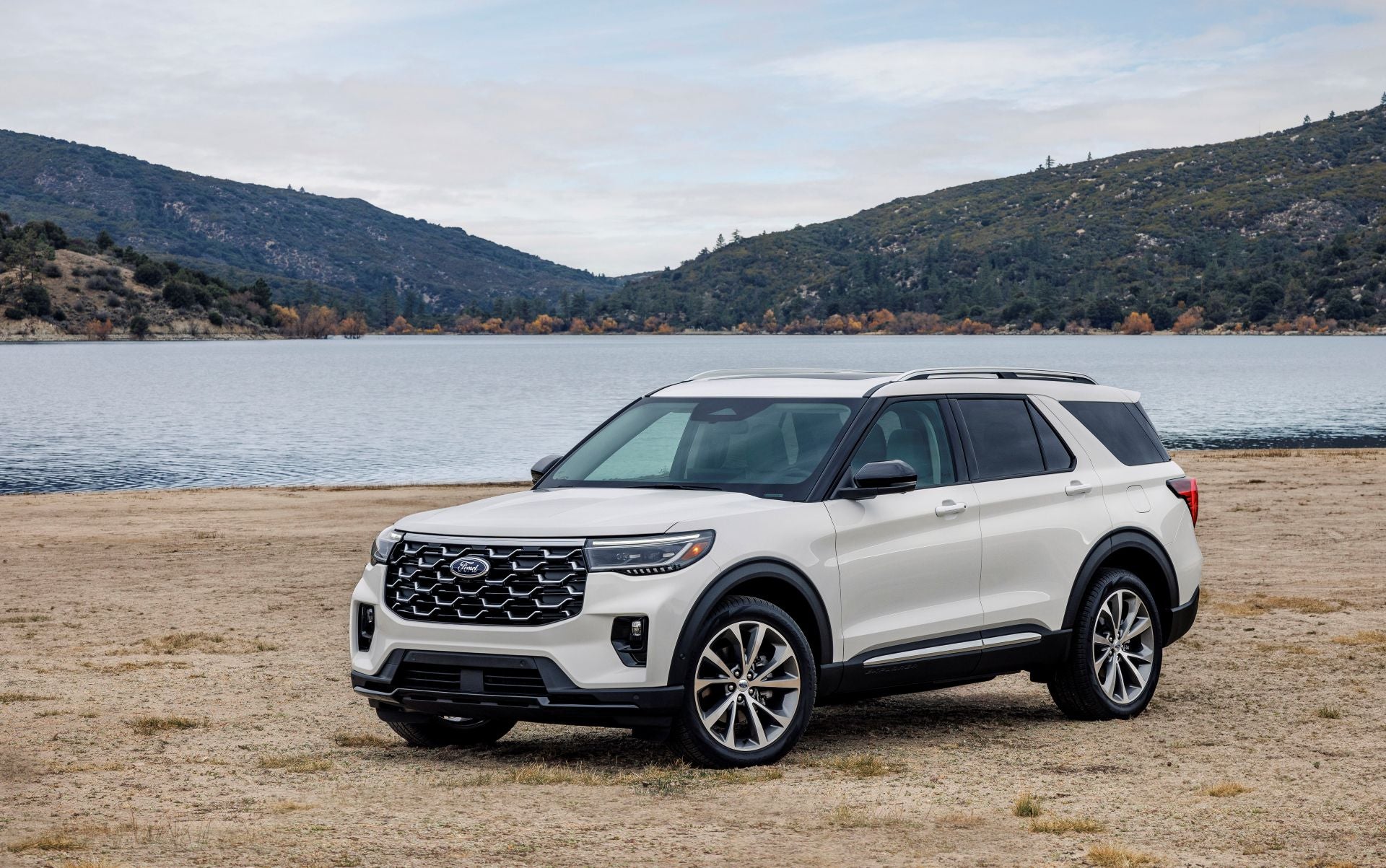 A white suv sitting parked by a body of water.