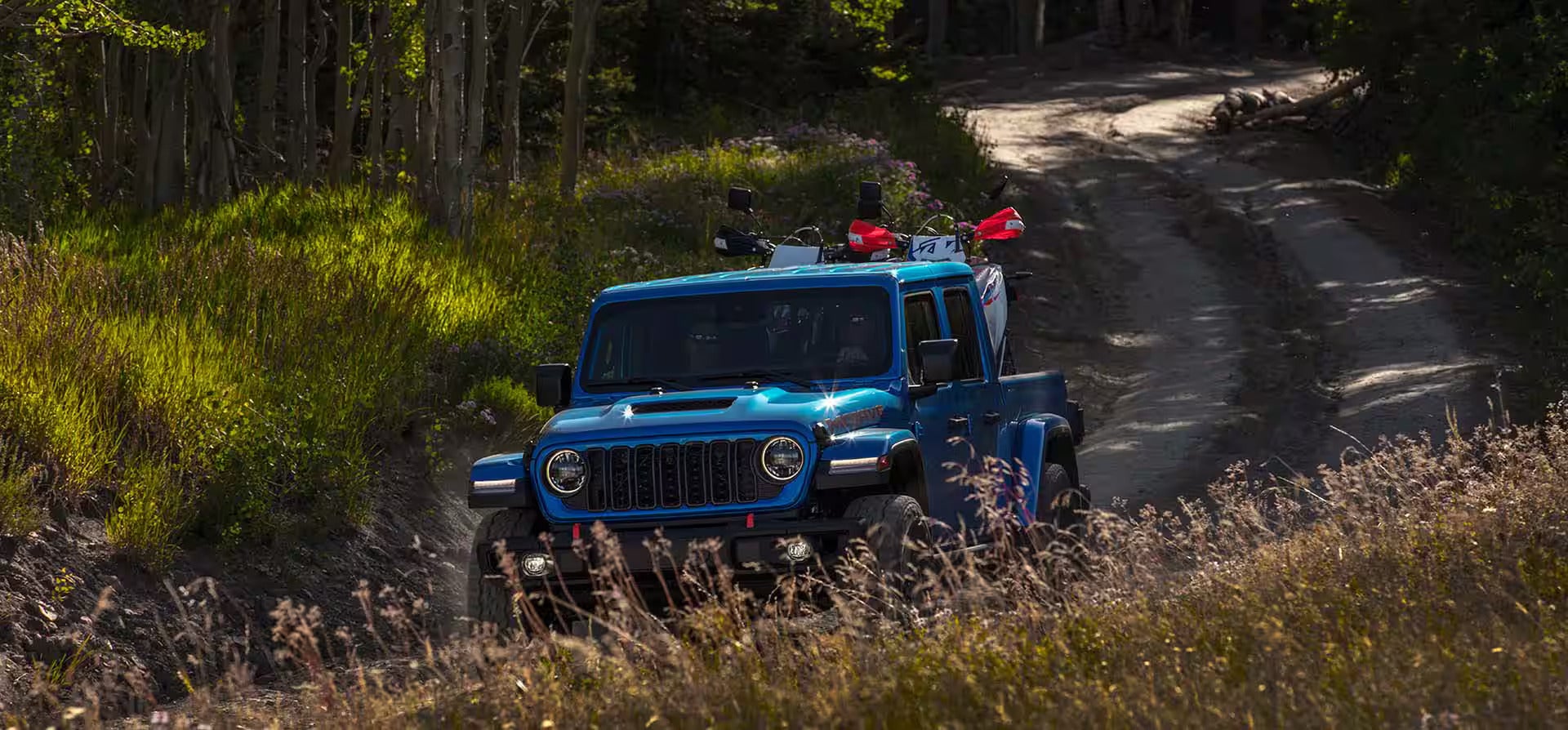 A blue jeep driving through tall grass.