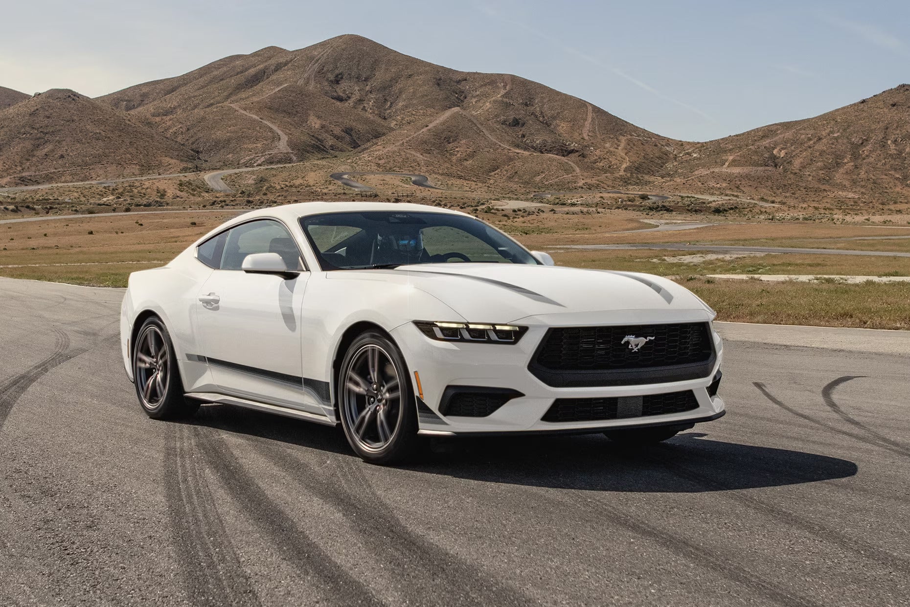 A white mustang on the road.