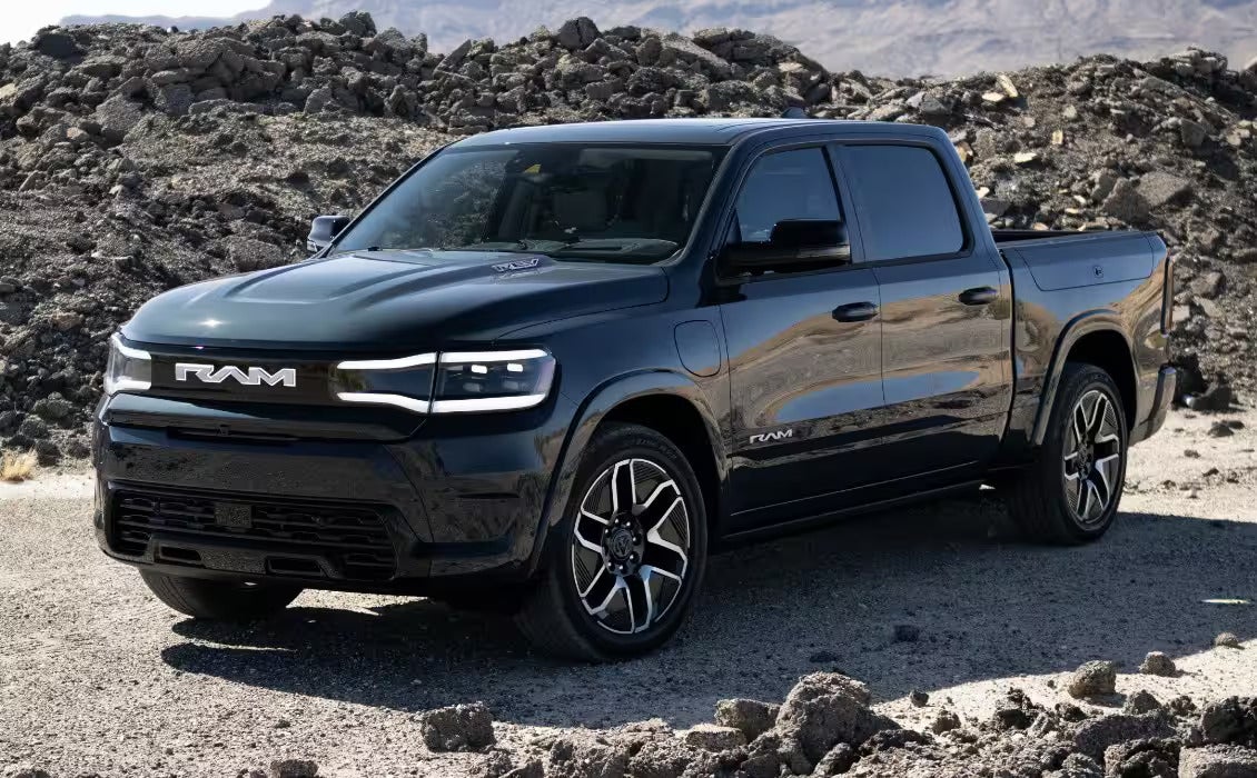 Black Ram 1500 REV electric truck parked in a rugged desert landscape with rocky terrain in the background.