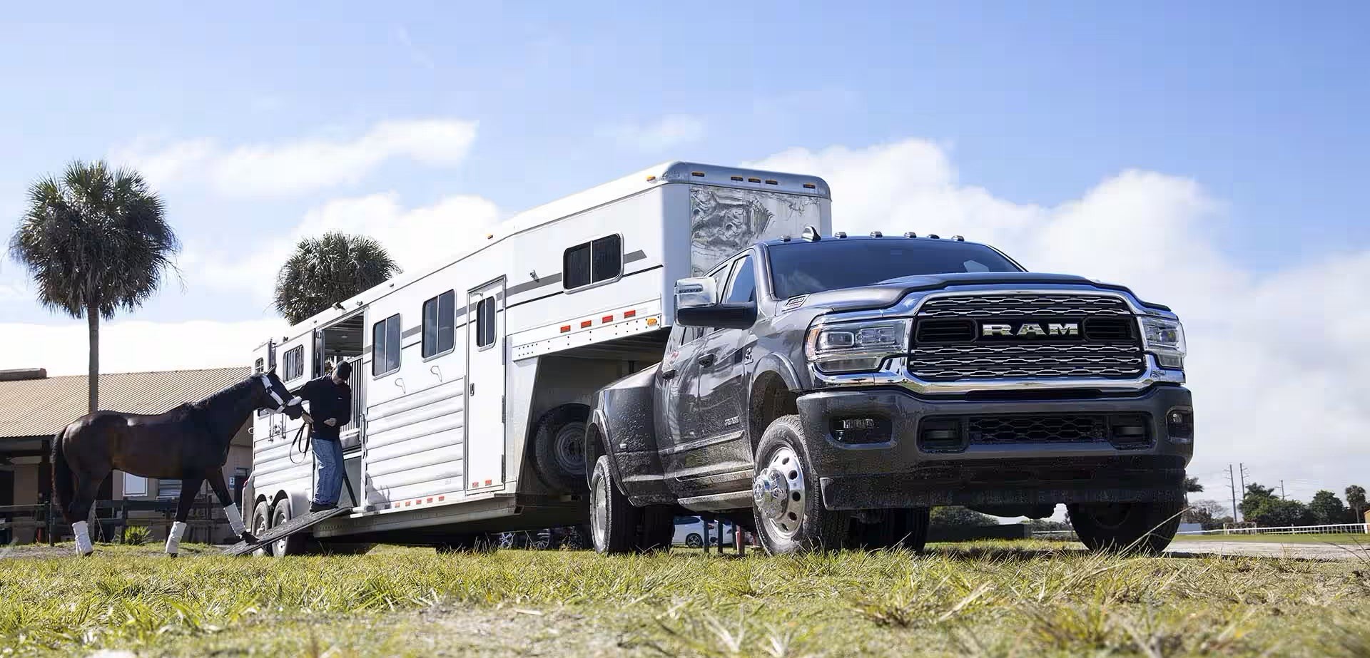 A truck sitting parked in the grass with a trailer.