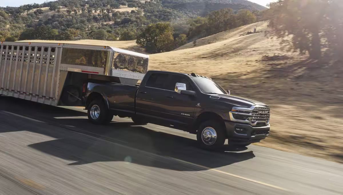 A black truck driving on the road with a trailer.