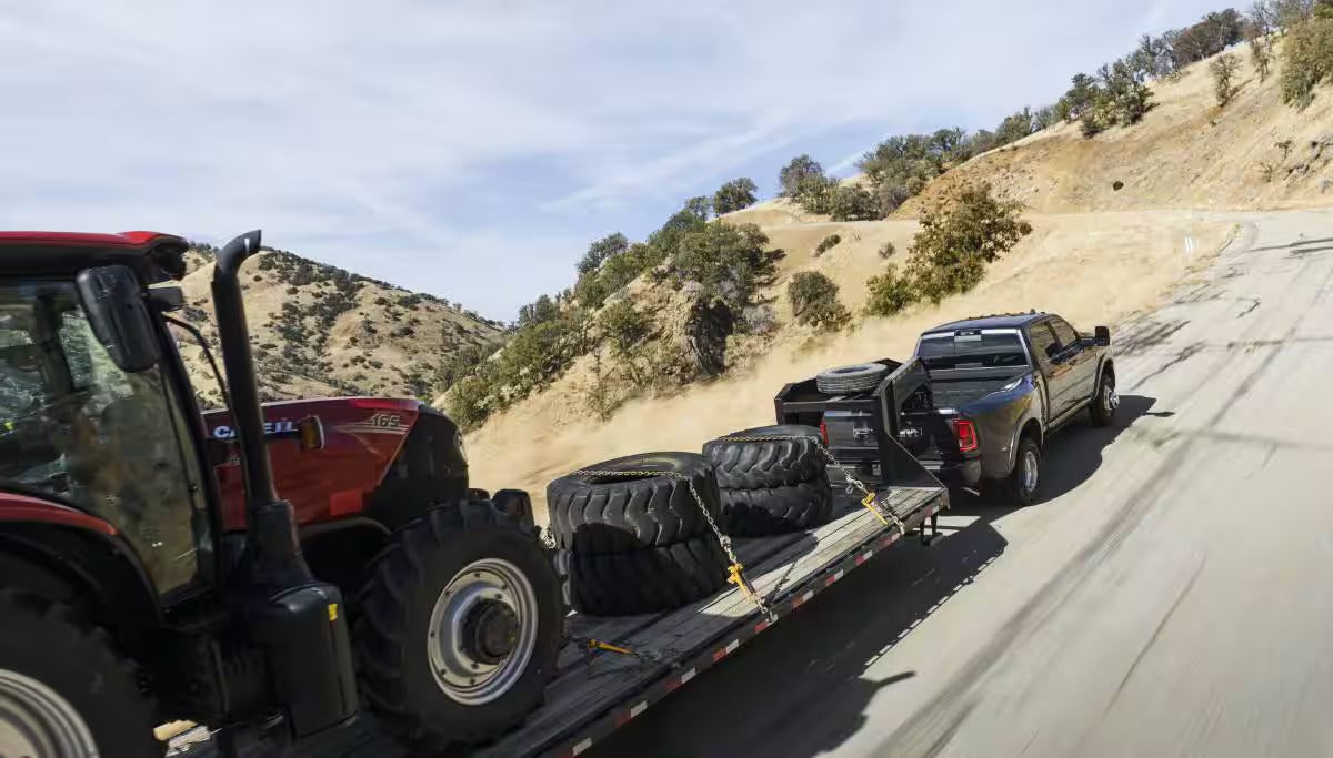 A black truck pulling a trailer on the road.
