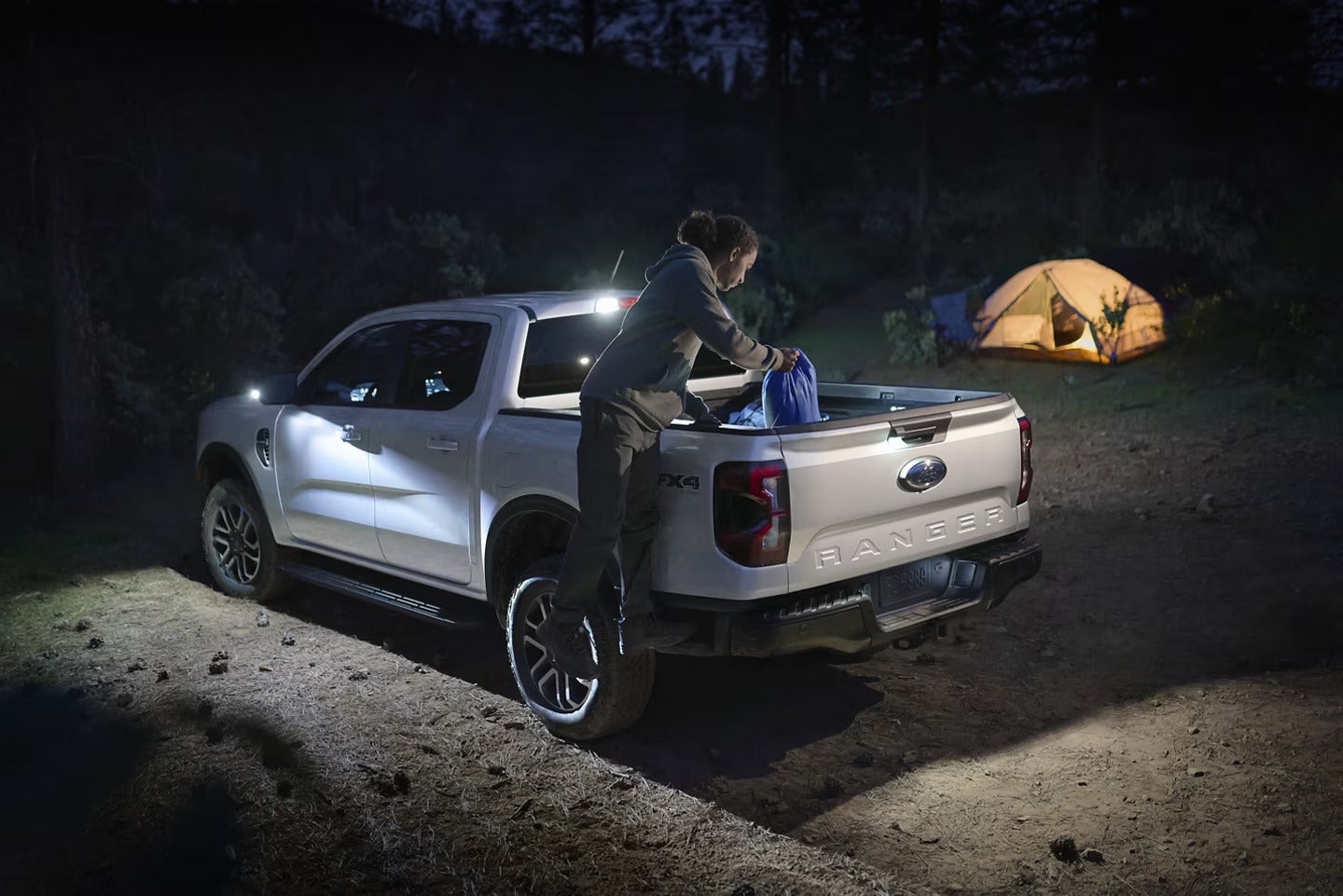 A person getting into the bed of a white truck.