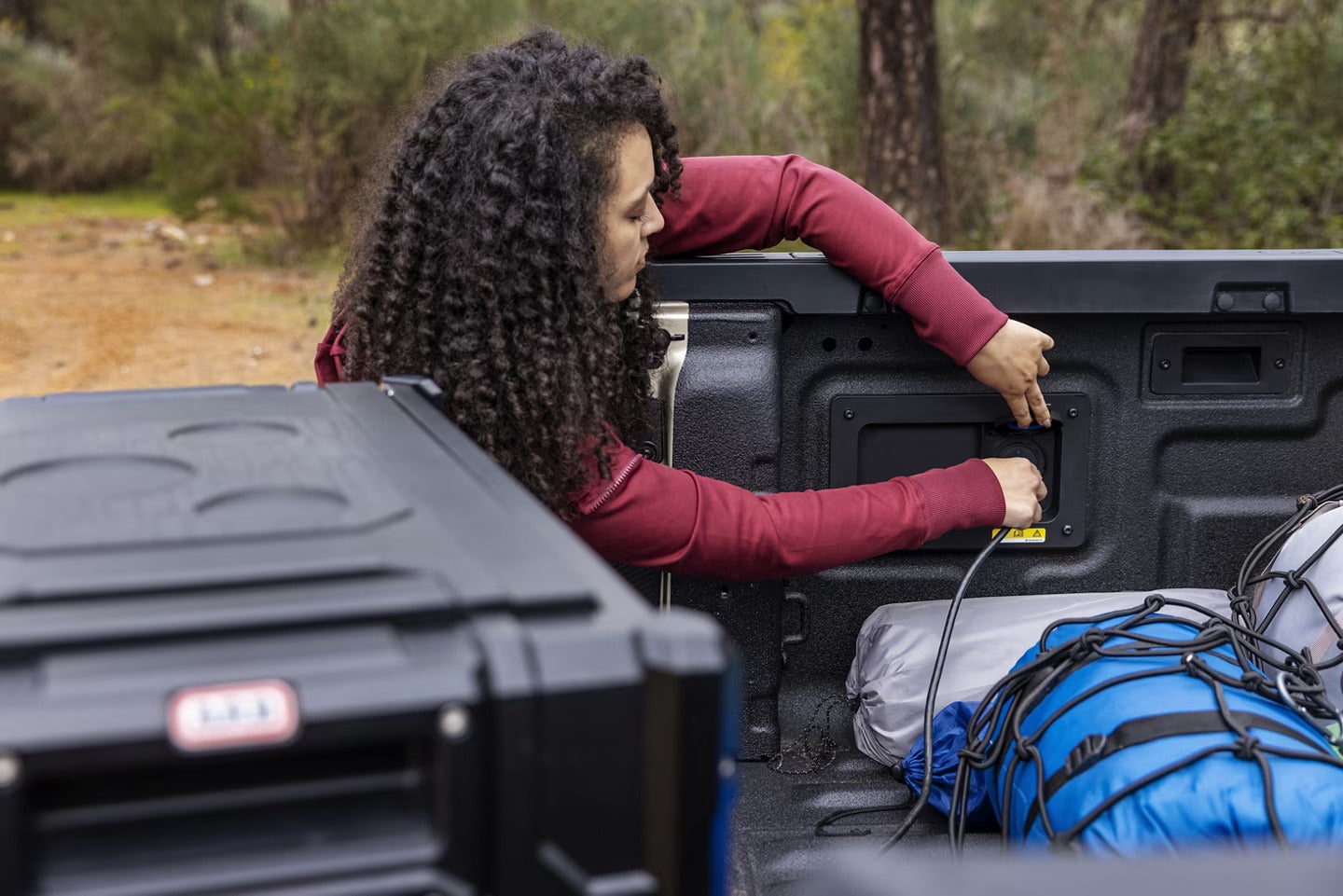 A woman plugging in some to the bed of a ford ranger.