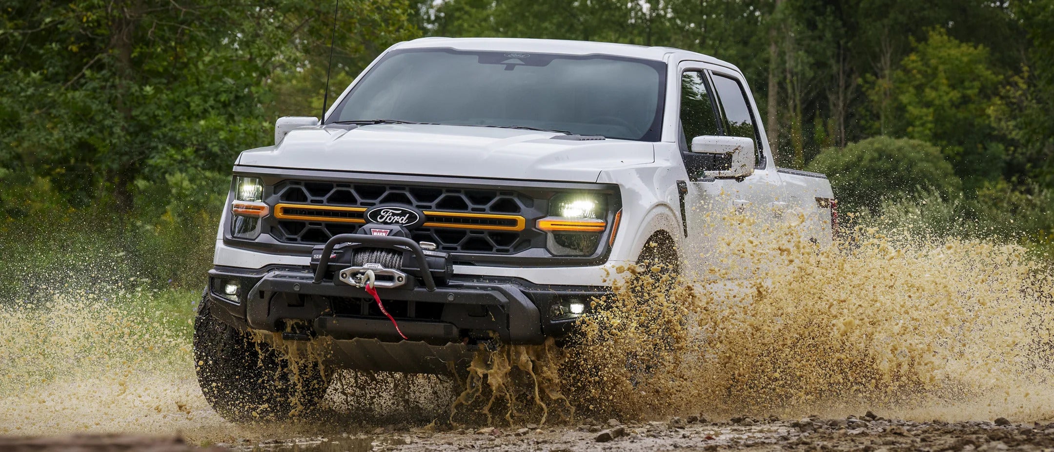 A white truck driving through muddy water.