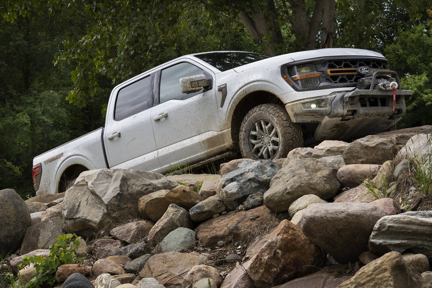 A white truck driving up some rocks.