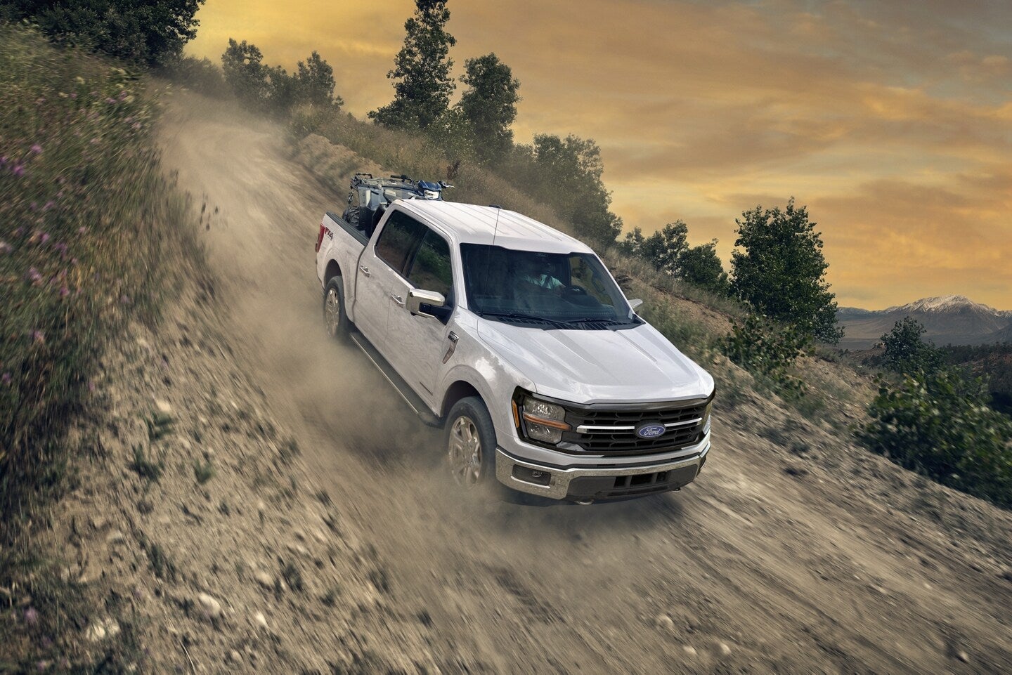 A white truck driving down a dirt hill.