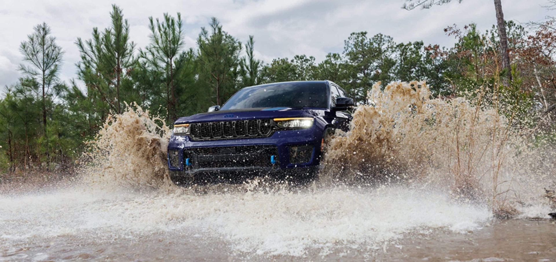 A blue jeep driving through some water.