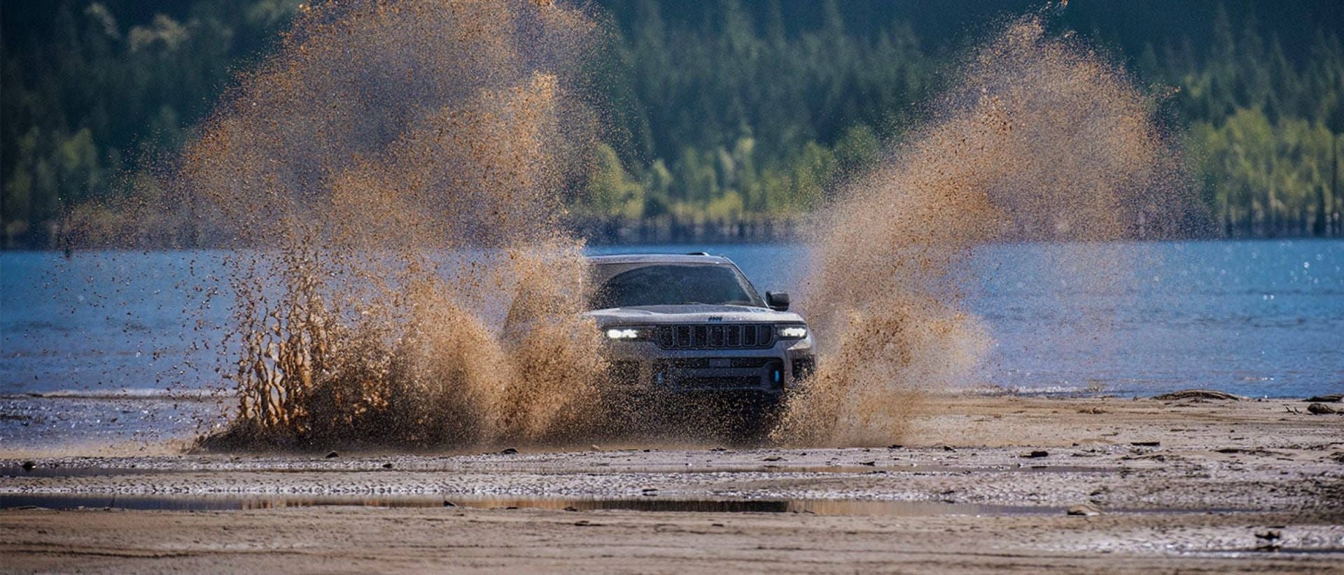 A silver suv driving through the mud.