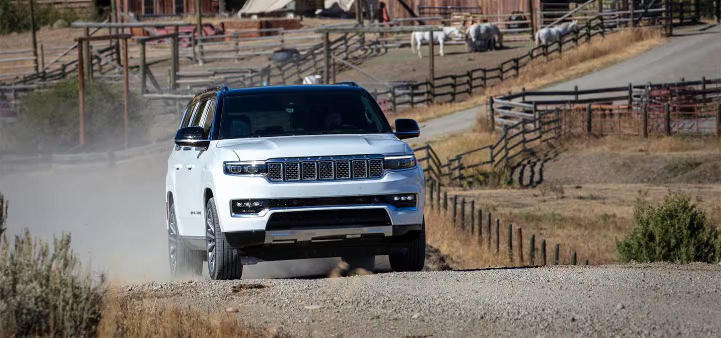 A white suv driving on a dirt road.