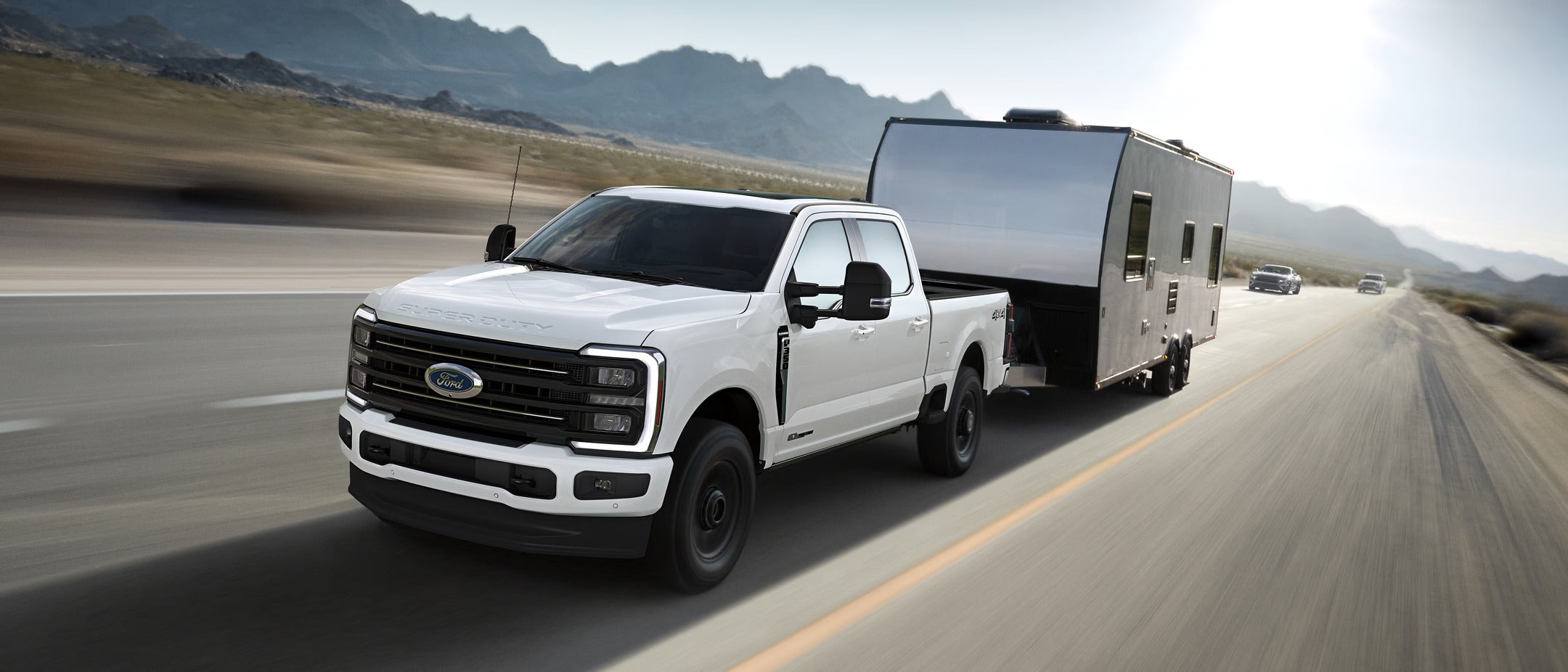 A white truck pulling a trailer on the road.