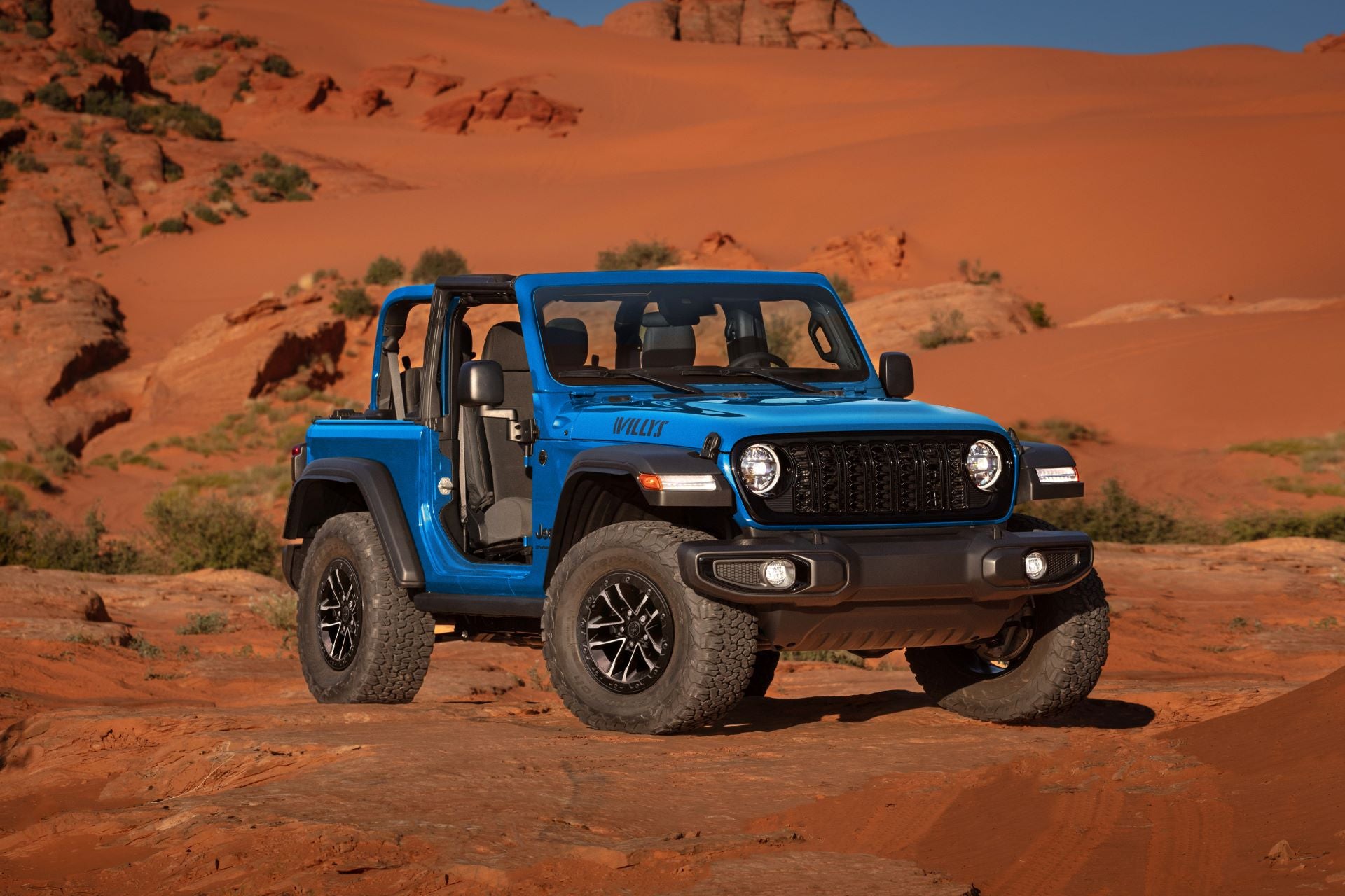 A blue jeep wrangler sitting parked with no doors.