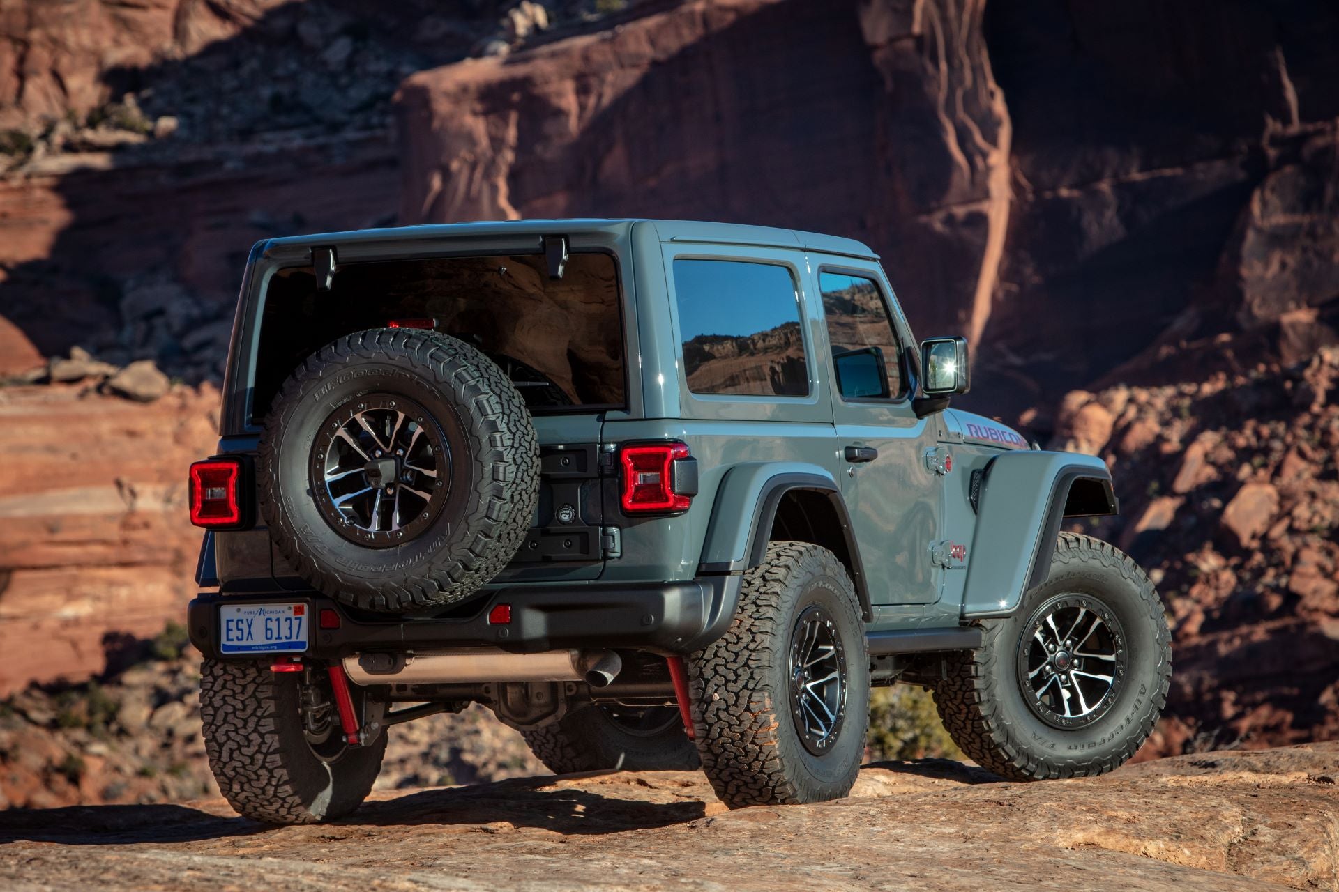 A gray jeep wrangler siiting up on some rocks.