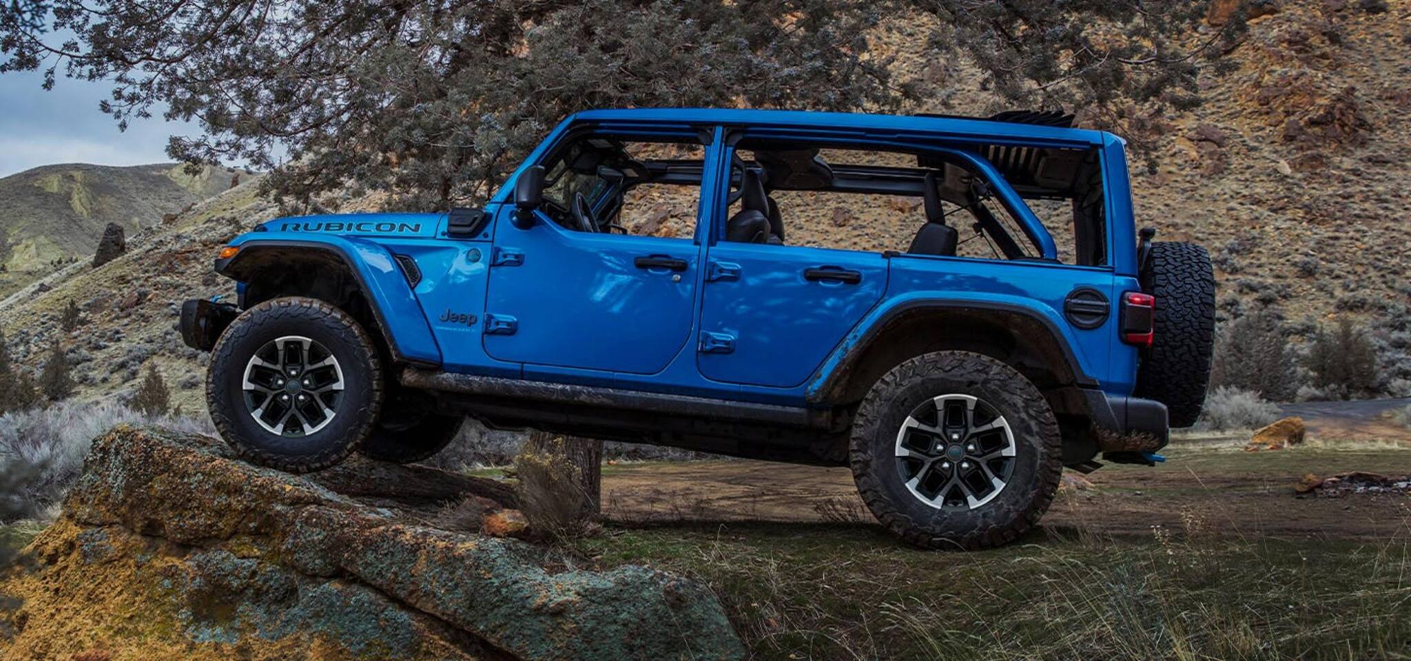 A blue jeep wrangler sitting up on some rocks.