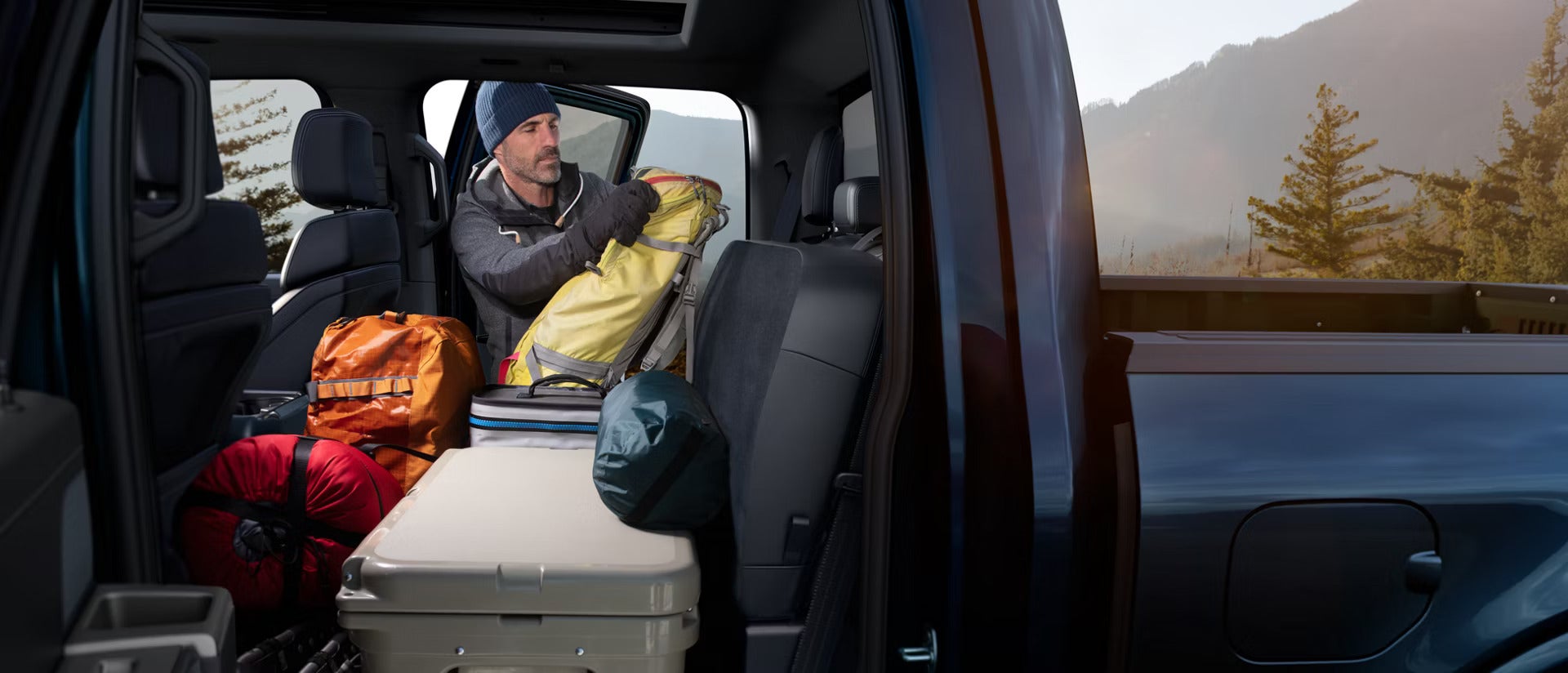 2026 Ford F-150 interior view of a man packing the back seat with camping gear