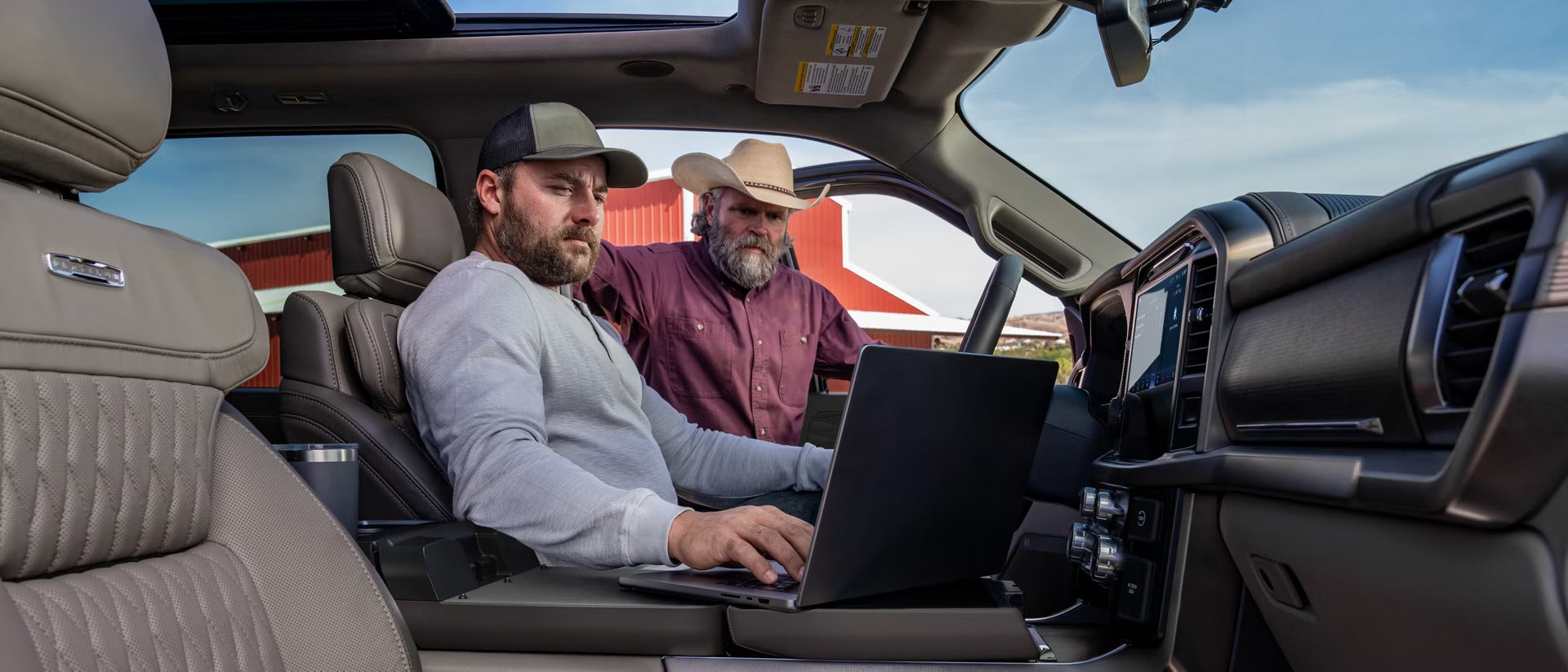 2026 Ford F-150 interior view of two men looking at a laptop sitting on the arm rest