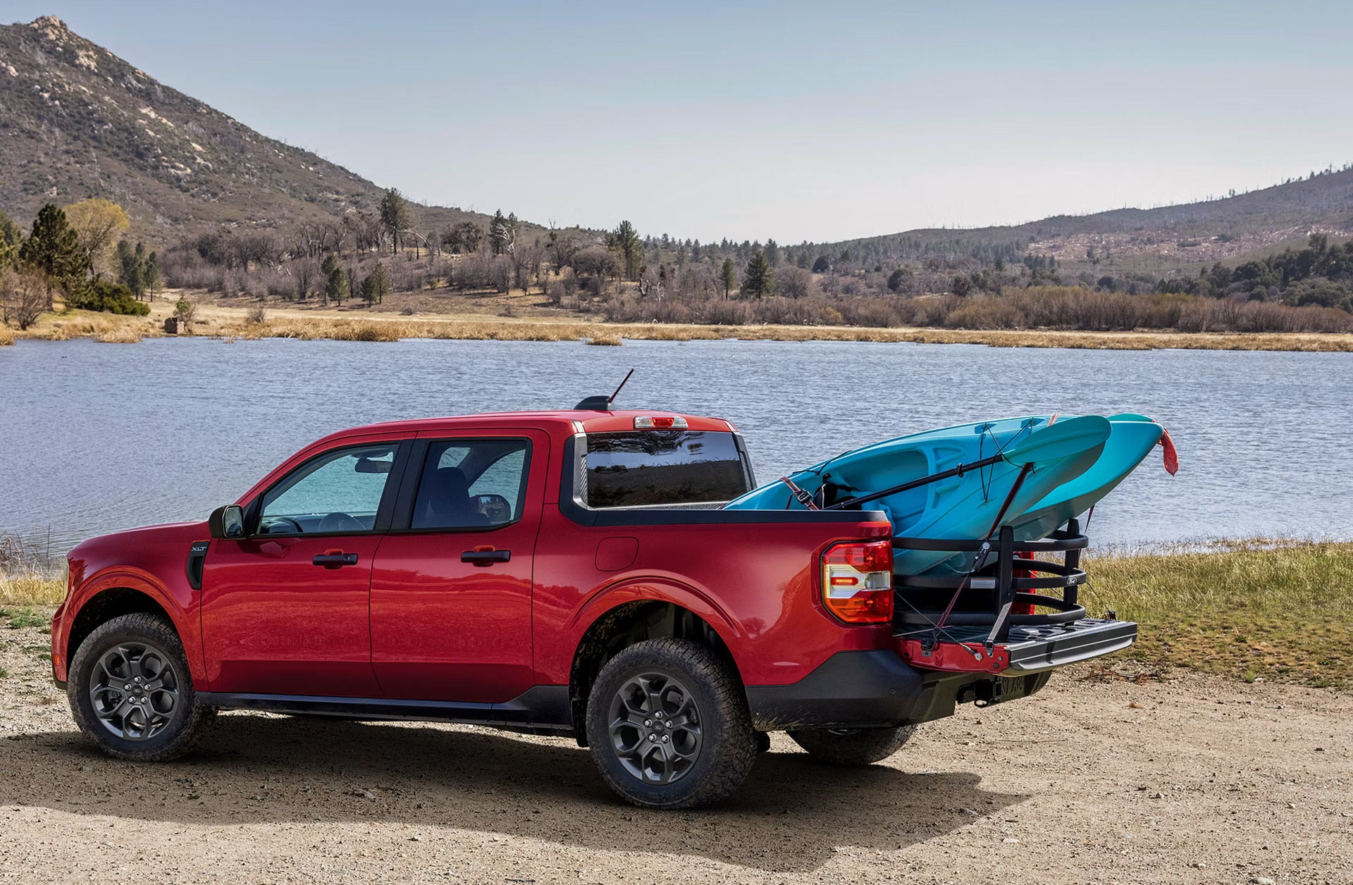 A New 2026 Ford Maverick parked next to a lake with a canoe sticking out of the bed