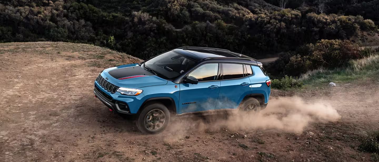 2026 Jeep Compass driving up a hill in the desert