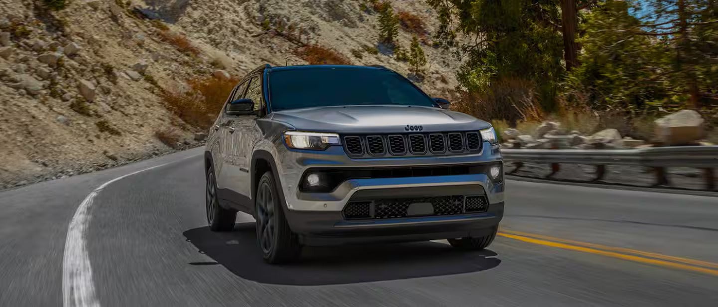 2026 Jeep Compass driving on a road in the mountains