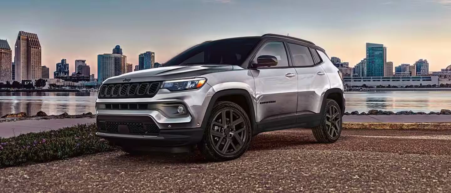 2026 jeep compass parked on a road with the city in the back ground