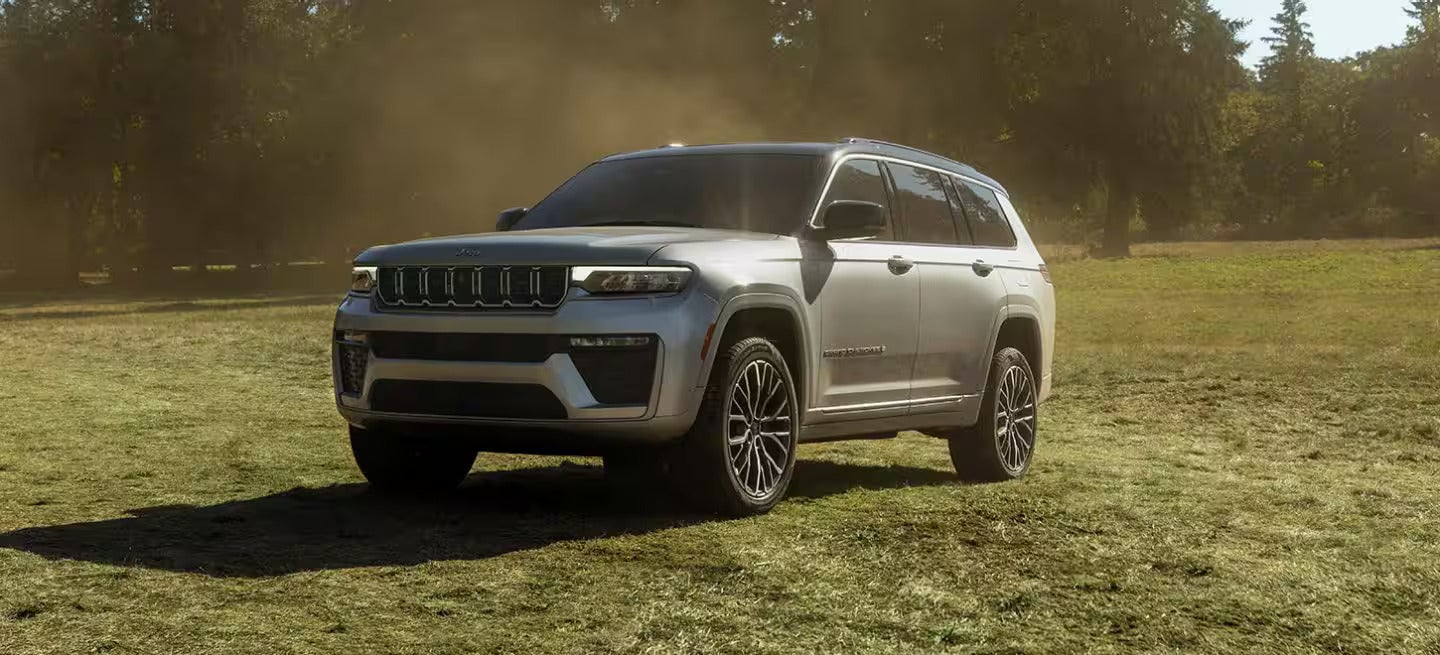 a new 2026 jeep grand cherokee parked on some grass in a field